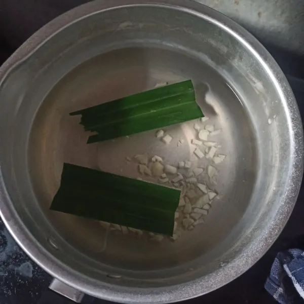 Masukkan bawang putih cincang dan daun pandan. Tunggu hingga air mulai panas.