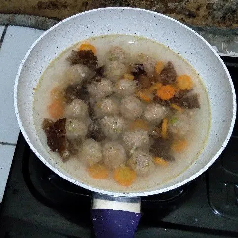 Tambahkan air, kemudian masukkan bakso, wortel, dan jamur kuping. Masak hingga wortel setengah matang.