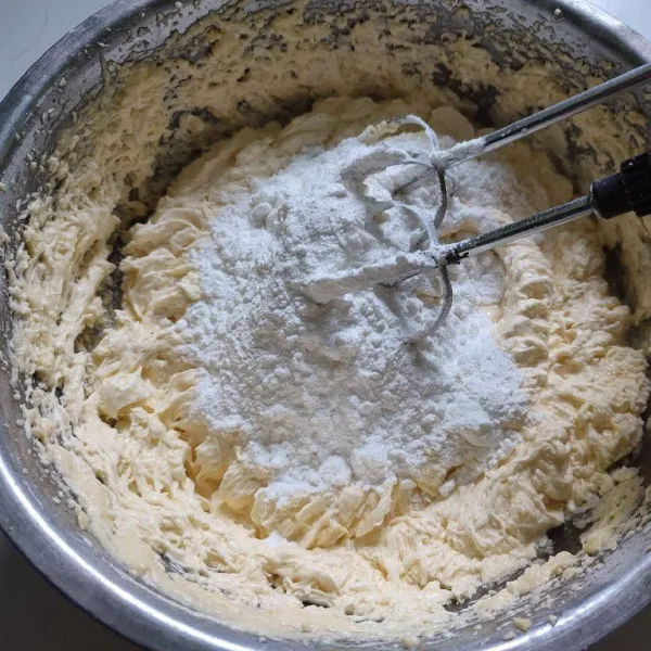 Kemudian masukkan secata bertahap tepung terigu dan tepung maizena, mixer kembali dengan kecepatan rendah hingga tercampur rata.
