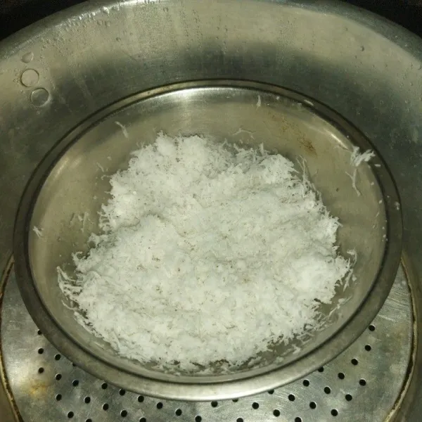 Siapkan kelapa parut setengah tua, beri garam, aduk rata, lalu kukus selama 10 menit.