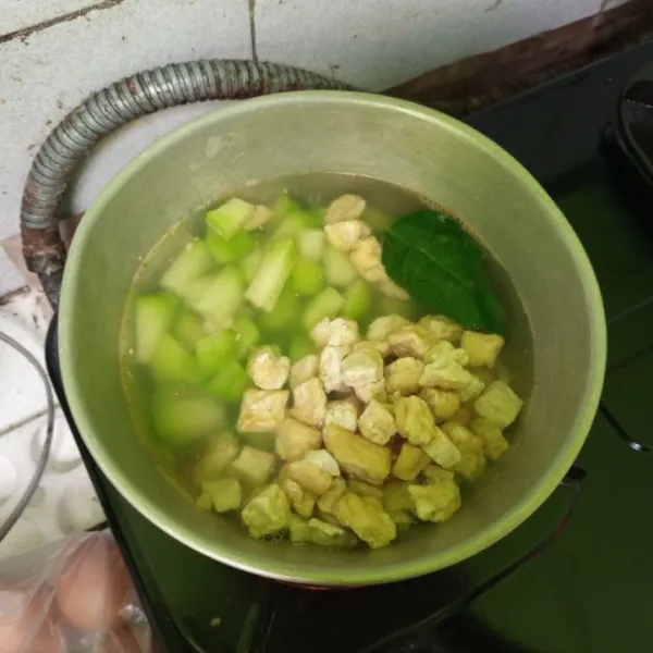 Masukkan potongan manisan, tahu, dan daun jeruk.