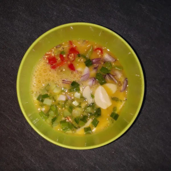 Campurkan irisan bawang merah, bawang putih, cabai rawit, dan daun bawang ke dalam telur. Aduk kembali sampai rata.