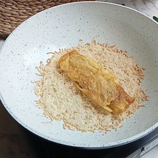 Masak dengan api kecil hingga keju krispi, kemudian taruh omelette di atas keju.