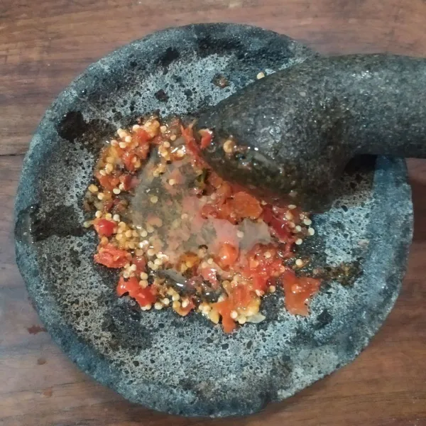 Haluskan cabai rawit, bawang putih, gula pasir, dan garam. Kemudian tuang minyak panas.