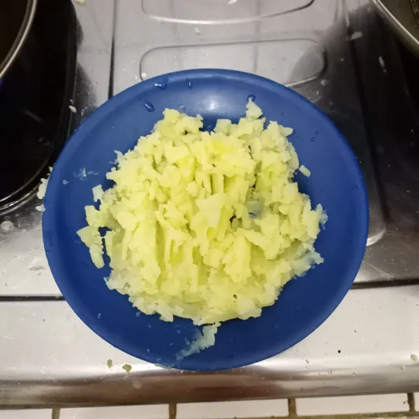 Potong kentang yang telah dikupas dan dicuci, lalu rebus dalam air mendidih hingga empuk, angkat dan tiriskan. 
Haluskan dengan garpu.