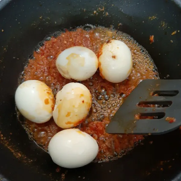 Beri garam, gula pasir dan air asam jawa serta masukkan telur rebusnya. Aduk rata hingga telur terbalut bumbu.