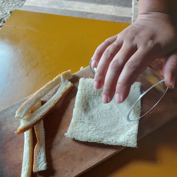 Potong bagian pinggir roti dan gilas/pipihkan dengan gelas.