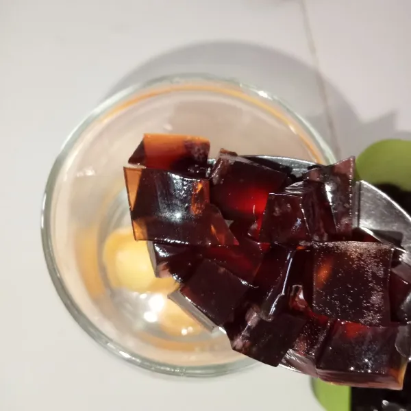 Dalam gelas saji masukkan es batu kemudian melon dan jelly