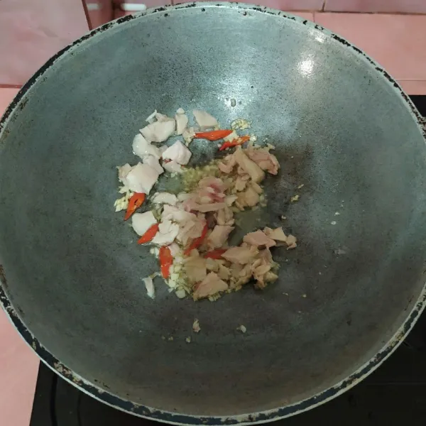 Tumis bawang putih cincang dan cabai.
Masukkan ayam, masak sampai ayam berubah warna.