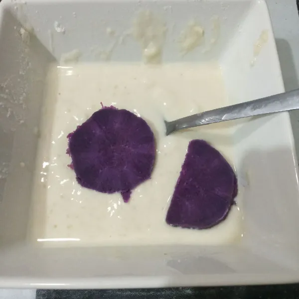Masukkan potongan ubi ke dalam adonan tepung.