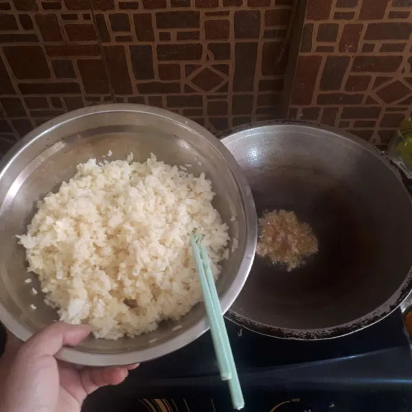 Tumis bawang putih hingga harum, masukkan nasi, gunakan api kecil agar telur tidak langsung meresap ke bulir nasi.