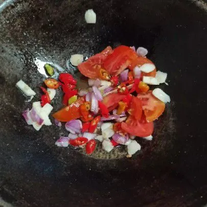 Tumis bawang putih, bawang merah, cabe rawit, dan tomat hingga harum.