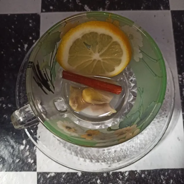 Letakkan lemon dan jahe di gelas. Lalu taruh kayu manis di gelas juga.
