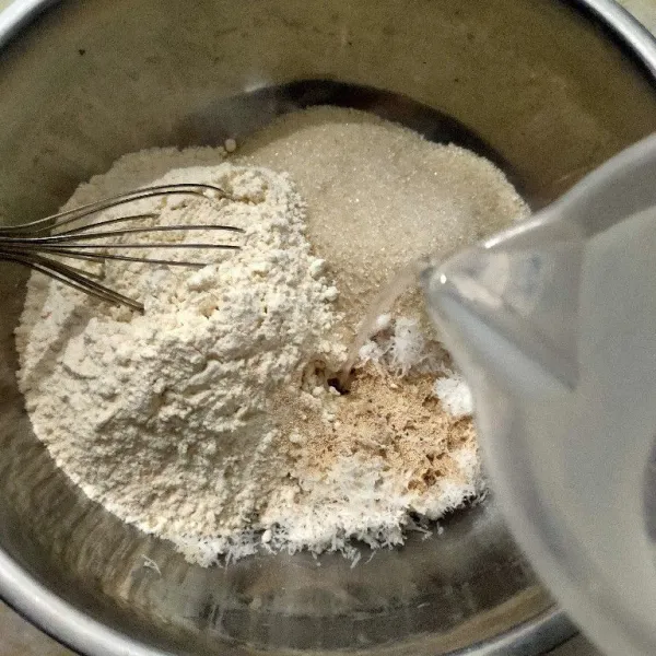 Campur jadi satu tepung, gula, ragi, kelapa, dan garam, tuang air dengan balon whisk aduk rata.