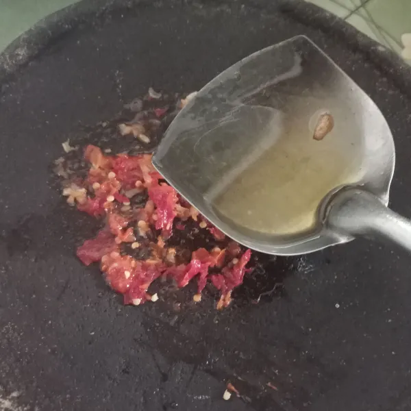 Uleg bahan sambal agak kasar dan siram dengan minyak panas, lalu tambahkan garam dan gula pasir. Kemudian aduk rata.