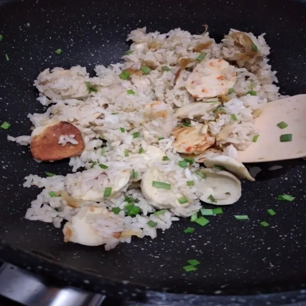 Masukkan nasi yang sudah dibumbui kecap ikan, tambahkan kaldu bubuk aduk rata masak hingha nasi tercampur dengan bumbu dan bahan lainnya, terakhir taburi dengan irisan daun bawang, koreksi rasa.