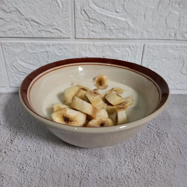 Kupas dan potong-potong pisang, lalu masukkan ke dalam mangkuk.