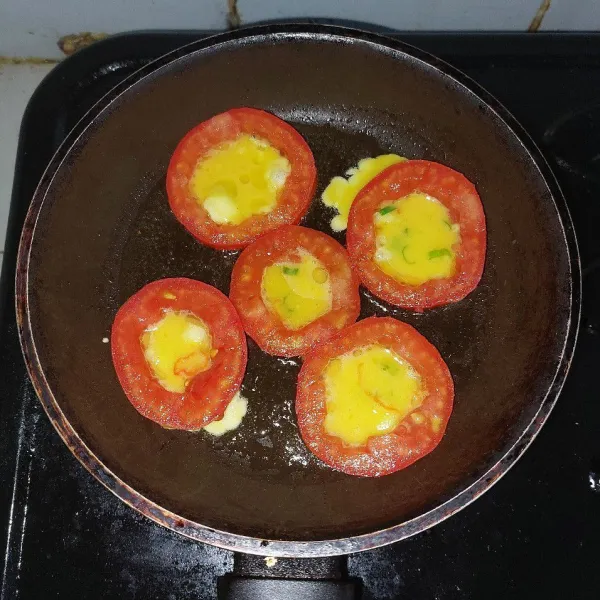 Setelah frypan panas. Masukkan tipis dulu adonan telur. Fungsinya untuk mengunci bagian bawah agar tidak banyak yang keluar dari tomat. Sesudah membuat kulit bagian bawah, baru masukkan lagi sisa telurnya. Masak hingga matang. Balik jika perlu.
