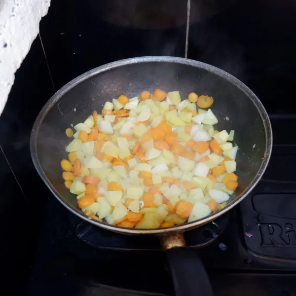 Tambahkan kentang dan wortel yang telah dipotong-potong. Masukkan air kaldu kemudian masak hingga sayur empuk.