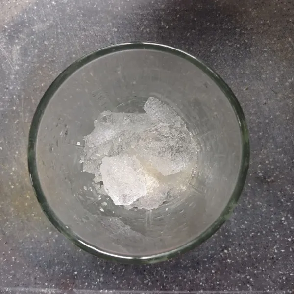 Siapkan es batu dalam gelas, tambahkan gula pasir.