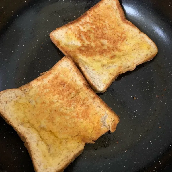 Oleskan mentega pada roti tawar lalu toast diatas pan hingga matang kecoklatan.