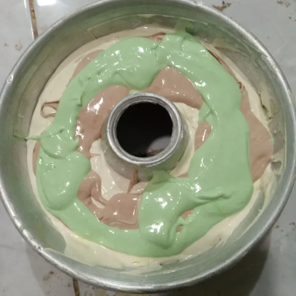 Tuang adonan putih, tambahkan sebagian adonan cokelat lalu hijau, lanjutkan kembali dengan sisa adonan.