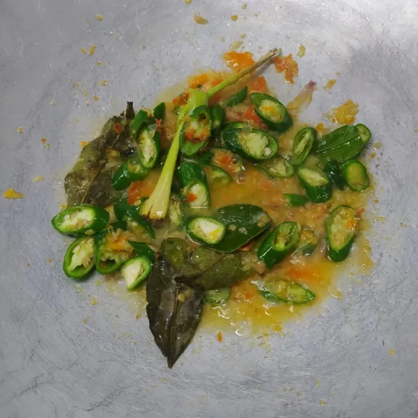 Masukkan serai, daun salam, daun jeruk, dan irisan cabai hijau. Tumis sampai wangi, lalu masukkan air.