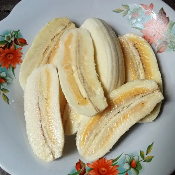 Kupas pisang dan belah dua.