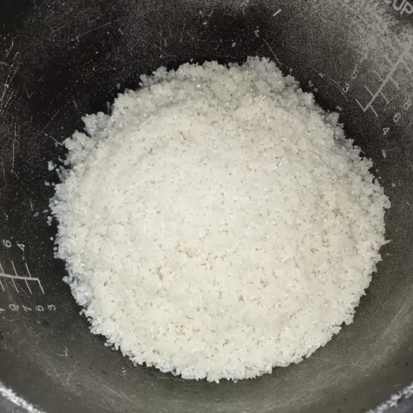 Cuci beras hingga bersih, lalu masukkan ke dalam rice cooker.
