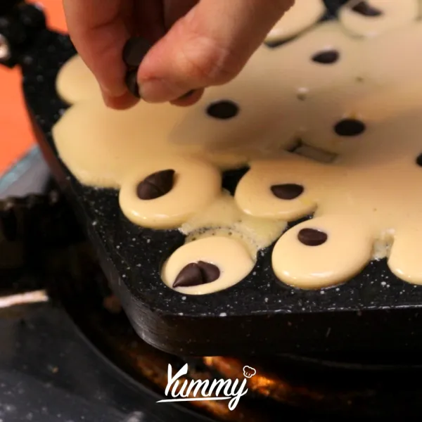 Panaskan cetakan egg waffle di atas kompor dengan api sedang. Tuangkan adonan waffle ke dalamnya, tambahkan topping dan tutup cetakan waffle, kemudian balik cetakan waffle.