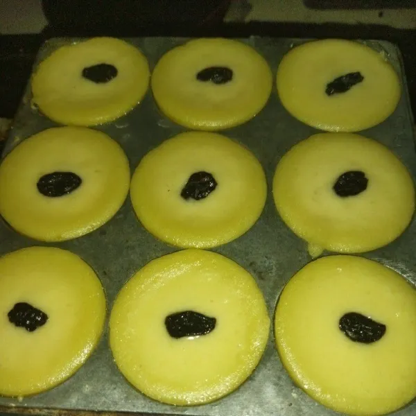 Jika kue sudah setengah matang, beri kismis di tengahnya, lalu tutup kembali, masak hingga kue lumpur matang.