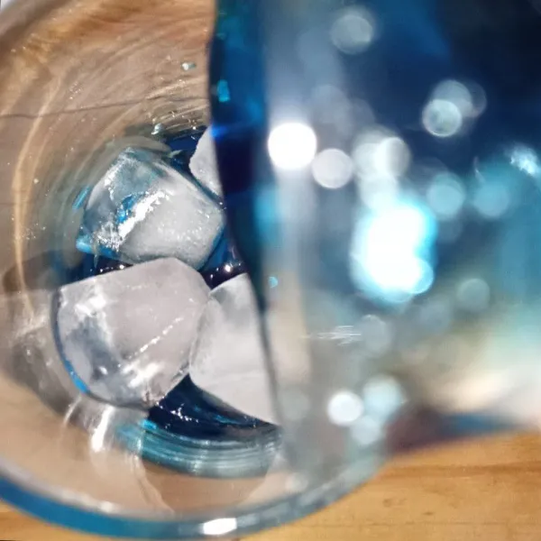 Masukkan sirup biru kedalam gelas berisi es batu.