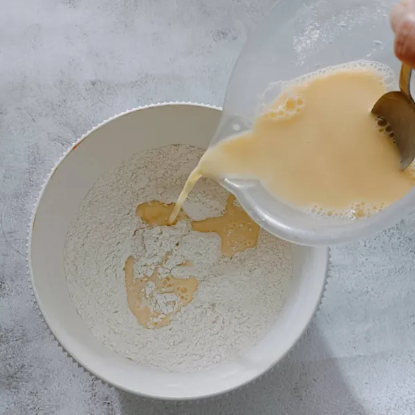 Campurkan susu UHT dan telur, kocok asal merata. Tuang sedikit demi sedikit kedalam wadah tepung sambil diaduk rata.