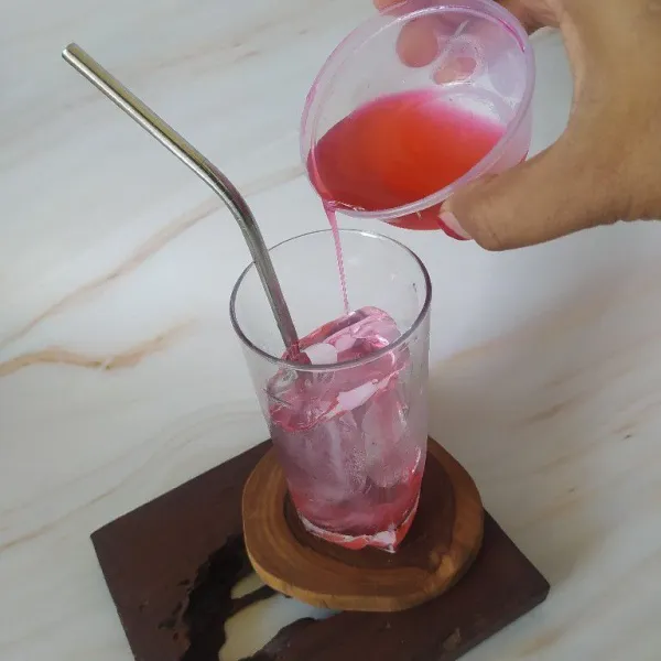 Tuang syrup ke dalam gelas yang berisi es batu.