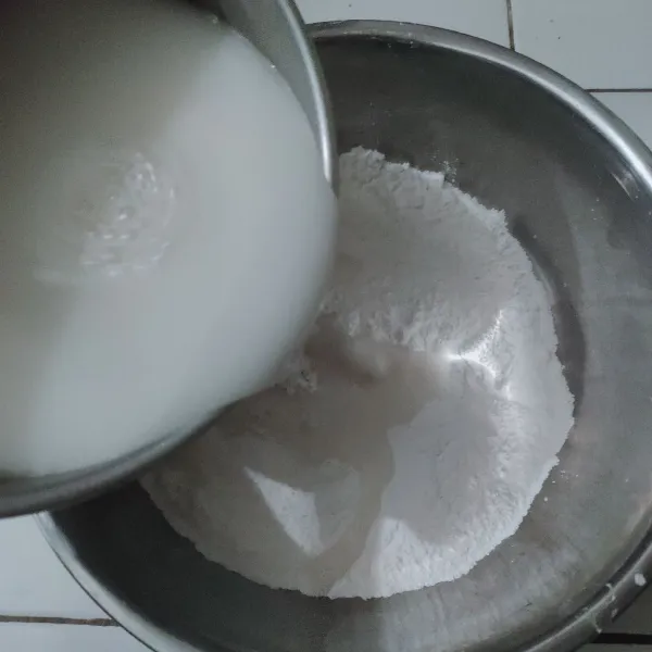 Tuang air santan ke dalam wadah berisi tepung beras dan tepung sagu yang sudah dicampur, aduk hingga rata.