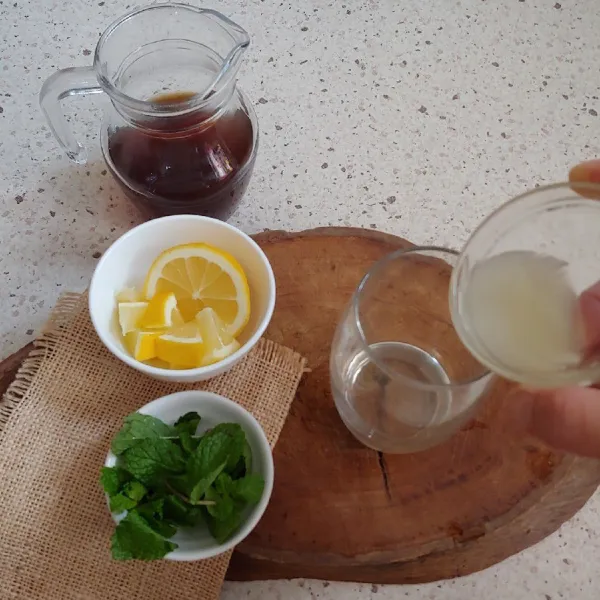 Tuangkan air perasan lemon, lemon slice dan es batu.