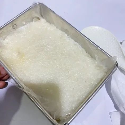 Siapkan loyang ukuran 10x15x4cm, masukkan setengahnya nasi ketan, ratakan diloyang yang dialasi dengan plastik.