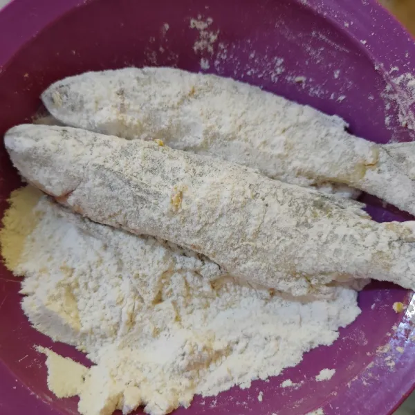 Masukkan ikan ke dalam campuran tepung, aduk hingga ikan terselimuti.