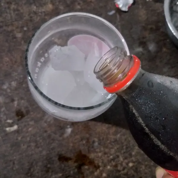 Tuang coca cola ke dalam gelas.