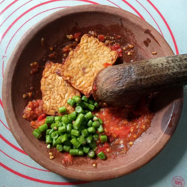 Tambahkan tempe dan kacang panjang, uleg temoe sampai hancur, cek rasa kembali.