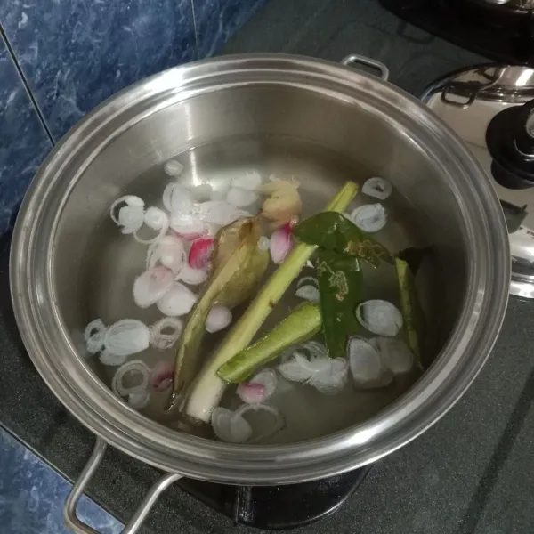 Dalam panci, didihkan air bersama bawang merah, bawang putih, serai, jahe, kunyit, lengkuas, daun jeruk dan daun salam.