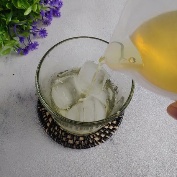 Tuang es batu di dalam gelas, lalu tambahkan chamomile tea hingga penuh. Sajikan.
