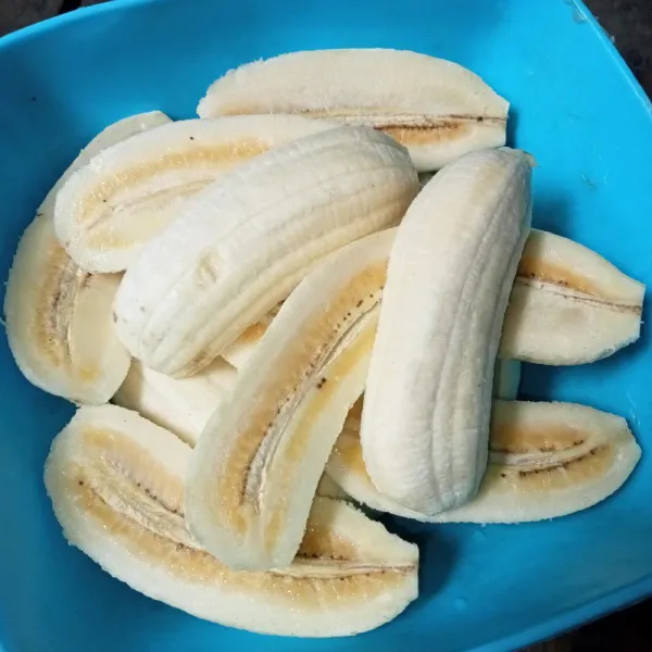 Kupas pisang dan belah dua.