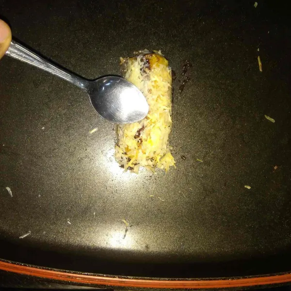 Telungkupkan keju parut secara perlahan menyelimuti pisang. Tekan-tekan menggunakan sendok agar keju menempel pada pisang. Angkat lalu sajikan hangat.