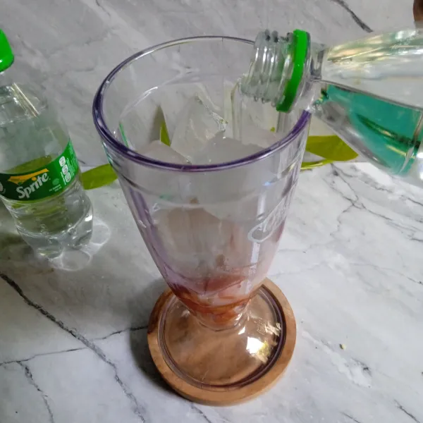 Tuang air soda ke dalam gelas saji.