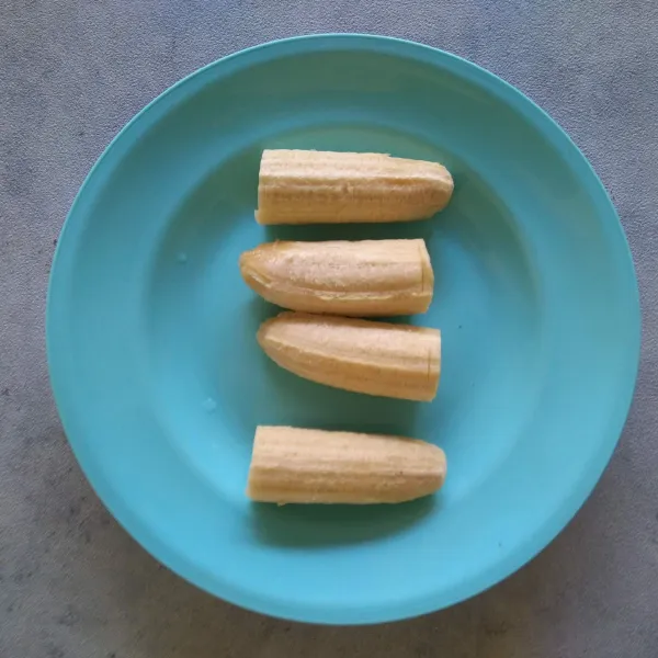 Kupas pisang lalu potong menjadi 2 bagian.