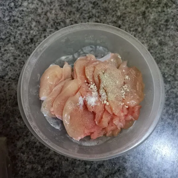 Iris tipis dada ayam kemudian lumuri dengan bumbu marinasi seperti garam, kaldu jamur dan merica bubuk, aduk rata.
