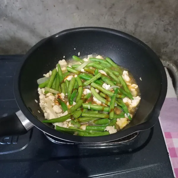 Tuang air dan kecap manis. 
Bumbui dengan garam, gula, lada dan kaldu bubuk. 
Masak sampai buncis setengah matang.