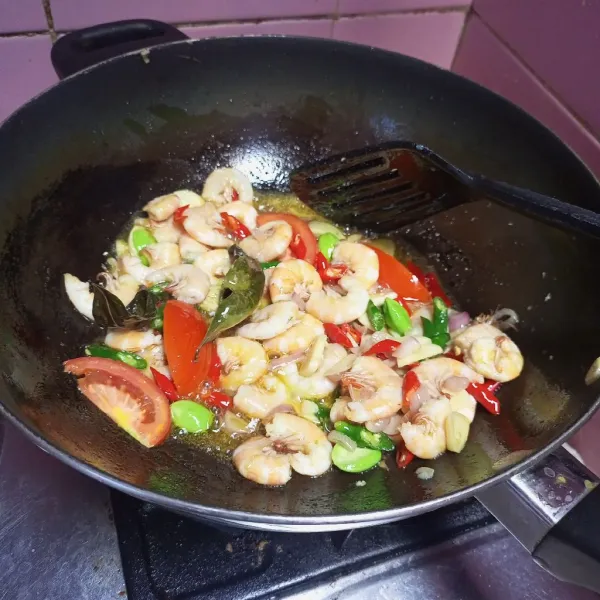 Tumis udang, cabe, bawang putih, bawang merah, tomat, petai dan daun salam hingga harum dan udang berubah warna.