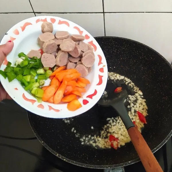 Masukkan irisan bakso, wortel dan daun bawang prei. Tambahkan sedikit air, Tumis hingga wortel layu.